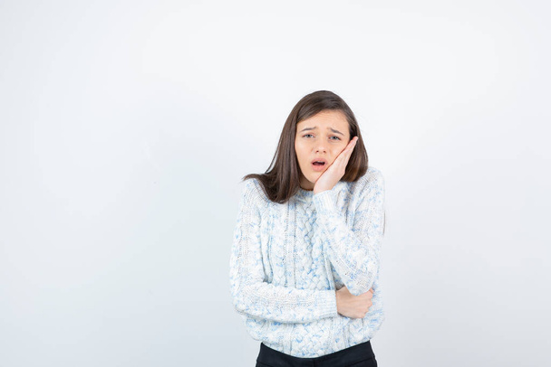 Beautiful young girl in knitted sweater standing and having toothache. High quality photo - Photo, Image