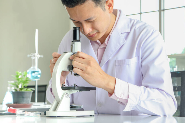 Азиатские ученые или химики используют микроскоп. В научном эксперименте Медицинские фармацевтические исследования концепция ДНК структуры, инноваций и технологий - Фото, изображение