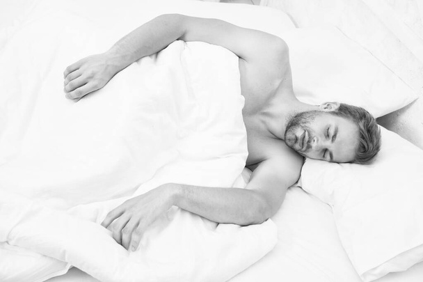 毎晩十分な量の睡眠。ヒントはよく眠る。髭を生やした男が枕で寛いでいる。柔らかい枕。ヘルスケアの概念。概日リズムは睡眠覚醒周期を調節する。男ハンサムなunshaven男でベッド - 写真・画像