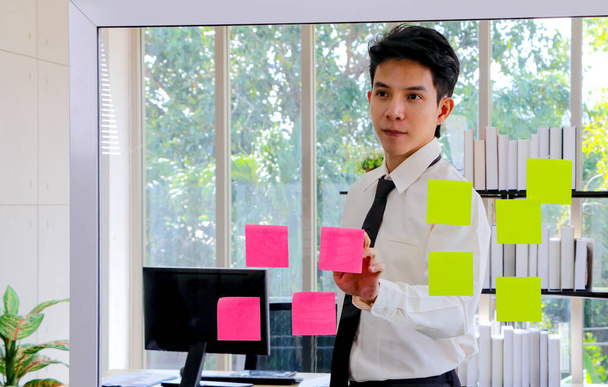 Azjatyccy biznesmeni szukają i piszą notatki na temat burzy mózgów. Umieść post na lustrze w biurze Plan pracy, burza mózgów, strategia Kreatywny styl życia, Sukces w biznesie Concept - Zdjęcie, obraz