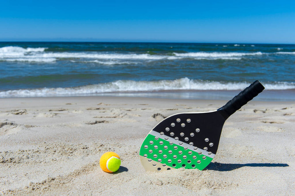 Racket and ball on the sandy beach. Summer sport concept - Photo, Image