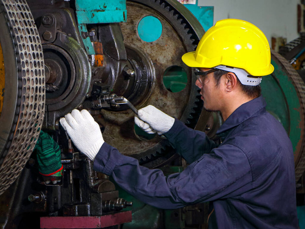 Asiatische Techniker Uniform Helm mit Schraubenschlüssel In der Maschineninspektion, das Konzept der Maschinensteuerung, Wartung und Kontrolle des Betriebs von Maschinen Arbeiten in Industrie- und Produktionsanlagen - Foto, Bild