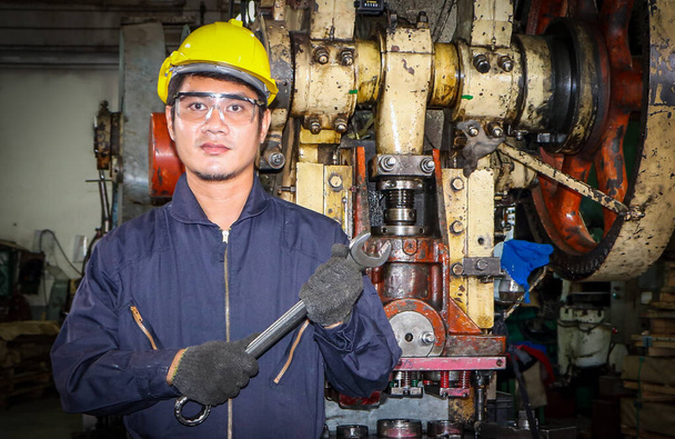 Azjatycki pracownik męski W przemysłach, które noszą okulary, czapki bezpieczeństwa i mundury bezpieczeństwa Klucz uchwyt na narzędzia stojak Konserwacja maszyn Koncepcja technika W branży z ufnością - Zdjęcie, obraz