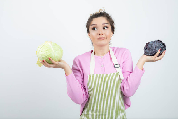 Young woman in apron with cabbages promoting healthy lifestyle. High quality photo - Photo, Image