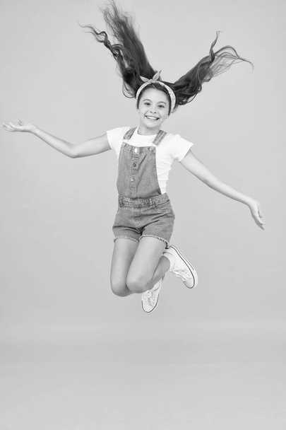 full of energy. Active girl feel freedom. Fun and relax. feeling free. carefree kid on summer holiday. time for fun. retro beauty in mid air. Jump of happiness. small girl jump yellow background - Фото, изображение
