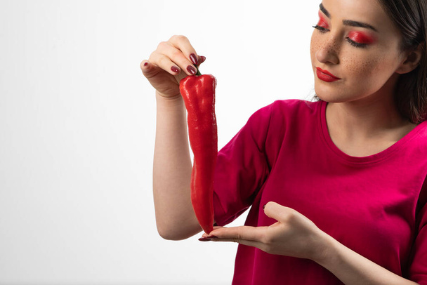Obraz młodej kobiety stojącej i trzymającej czerwoną ostrą paprykę chili. Wysokiej jakości zdjęcie - Zdjęcie, obraz