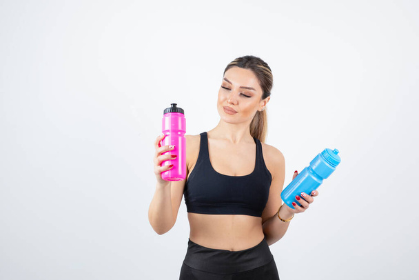 Beautiful sporty woman holding bottles with water on white background. High quality photo - Foto, Imagem