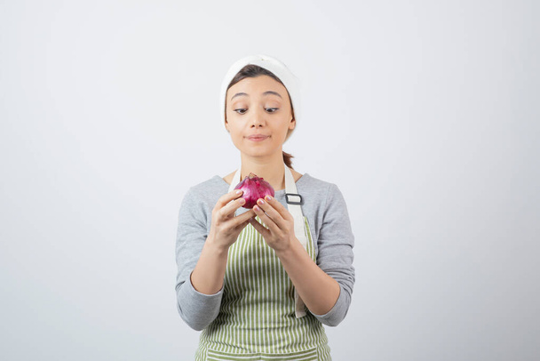 Photo of a good-looking woman model in apron holding a purple onion . High quality photo - Fotografie, Obrázek