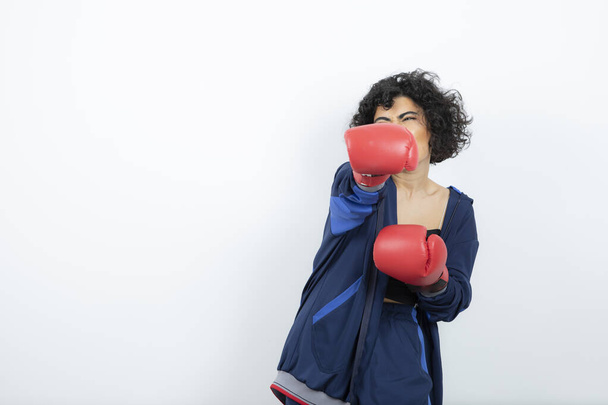 Photo of curly haired female athlete in red gloves training. High quality photo - Фото, зображення