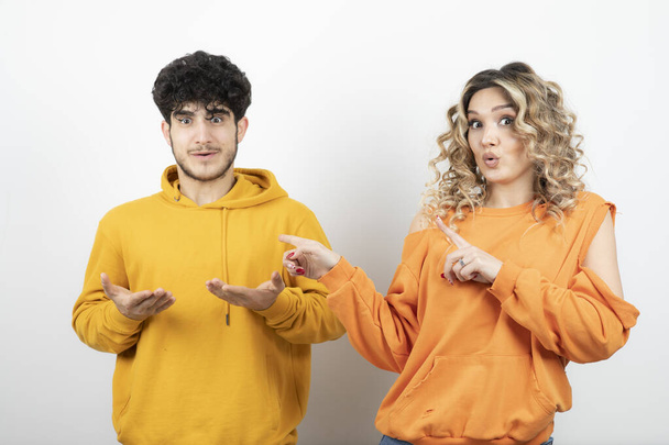 Pair of attractive lovers in yellow sweaters showing some signs. High quality photo - Photo, Image