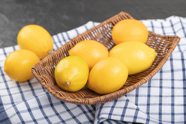 Желтые спелые свежие лимоны в плетеной корзине со скатертью. Высокое качество фото - Фото, изображение