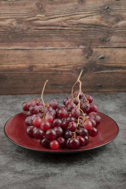 Red plate of fresh grapes placed on marble surface. High quality photo - Foto, imagen