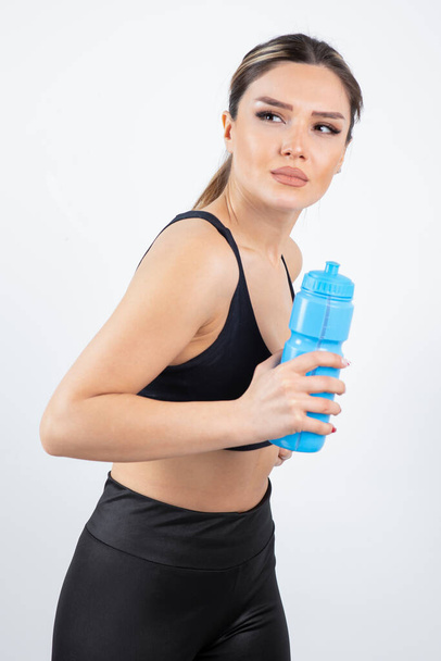 Portrait of young athletic woman holding blue water bottle. High quality photo - Foto, Bild