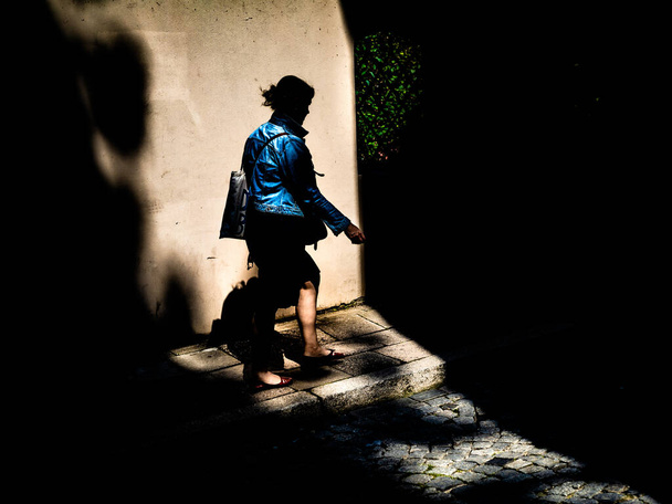 silhouet van de vrouw op straat in het zonlicht - Foto, afbeelding