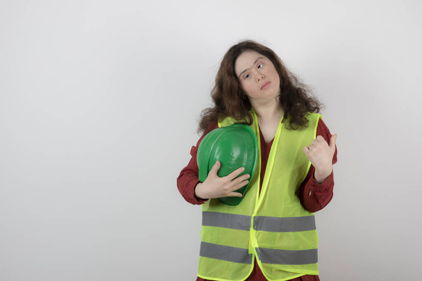 Obrázek mladé roztomilé dívky s Downovým syndromem, jak stojí ve vestě a drží helmy. Kvalitní fotografie - Fotografie, Obrázek