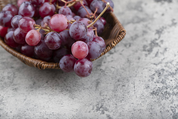 Wicker basket of fresh red grapes on stone background. High quality photo - Photo, Image