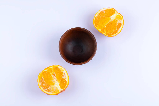 Vide bol en bois avec des tranches de fruits orange placé sur un fond blanc. Photo de haute qualité - Photo, image