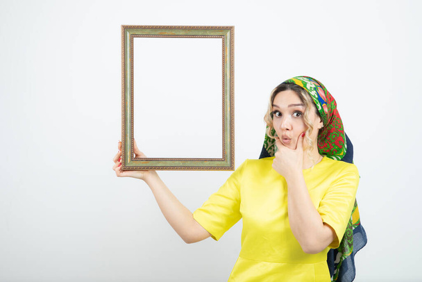 Photo of cute woman in headkerchief holding frame . High quality photo - Photo, Image