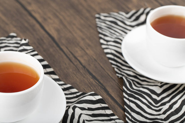 Білі чашки гарячого смачного чаю поміщають на дерев'яний стіл. Високоякісна фотографія
 - Фото, зображення