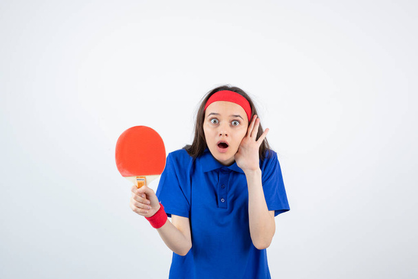Foto eines jungen Mädchens, das einen Tischtennisschläger über eine weiße Wand hält. Hochwertiges Foto - Foto, Bild