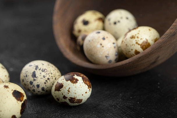 Wooden bowl of raw quail eggs on black background. High quality photo - Photo, Image
