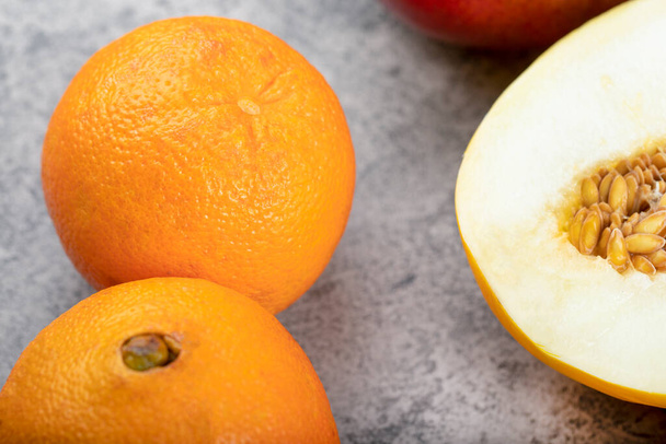 Geel gesneden meloen en verse sinaasappels op stenen ondergrond. Hoge kwaliteit foto - Foto, afbeelding