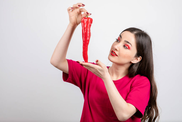 Εικόνα της μελαχρινής γυναίκας που κοιτάζει κόκκινο καυτερό πιπέρι τσίλι. Υψηλής ποιότητας φωτογραφία - Φωτογραφία, εικόνα
