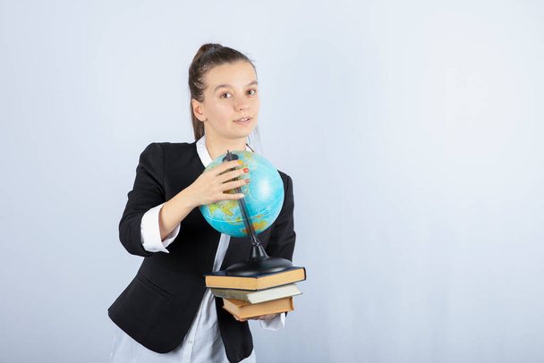 Foto de una hermosa maestra joven con libros y globo de pie sobre fondo blanco. Foto de alta calidad - Foto, Imagen