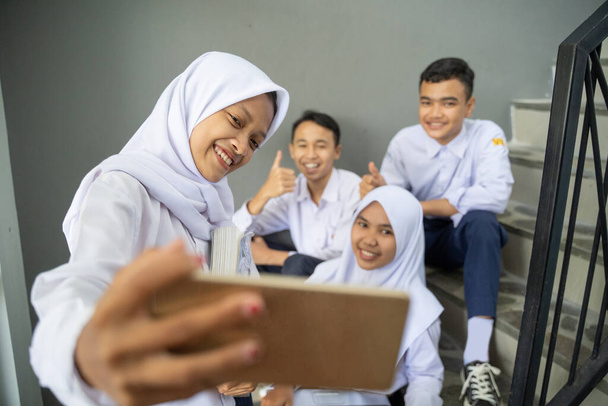 a group of teenagers in school uniforms taking selfies along with a cellphone - Foto, Bild