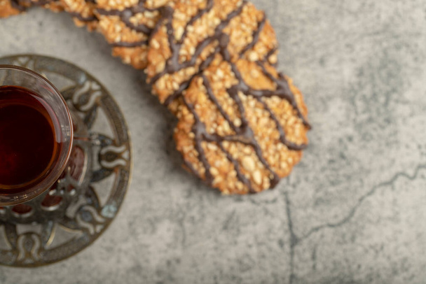 Oat chocolate biscuits with glass of black tea on stone. High quality photo - Photo, Image
