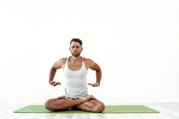 Male yoga maditates in classical pose in studio over white background - Фото, изображение