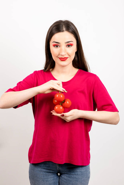 Beautiful girl looking at camera and holding red tomatoes in the hands . High quality photo - Foto, afbeelding