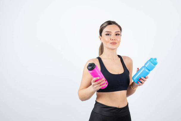 Schöne sportliche Frau hält Flaschen mit Wasser auf weißem Hintergrund. Hochwertiges Foto - Foto, Bild