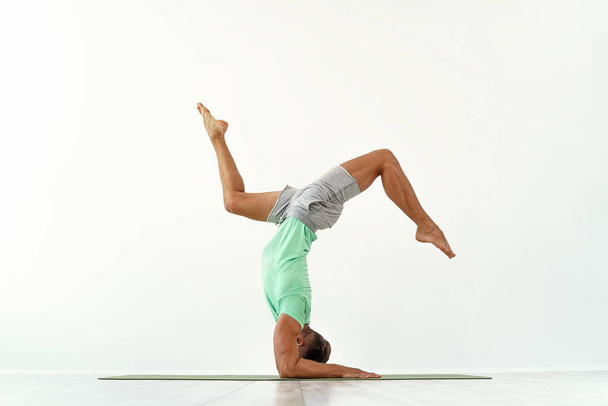 Man practicing balance yoga pose on white studio background. - Φωτογραφία, εικόνα