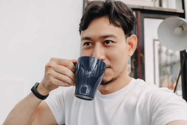 Happy man is drinking hot drink coffee in the cafe. - Φωτογραφία, εικόνα