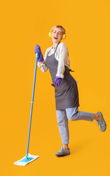 Young woman with floor mop on color background - Фото, изображение