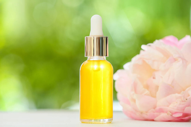 Бутылка эфирного масла и цветка на открытом воздухе - Фото, изображение