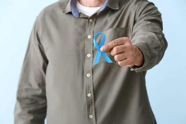 Hombre con cinta azul sobre fondo de color, primer plano. Concepto de cáncer de próstata - Foto, Imagen