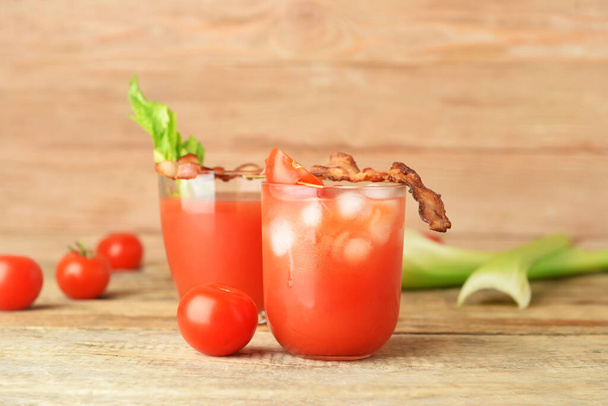 Glasses of bloody mary cocktail garnished with bacon on wooden background - Photo, Image
