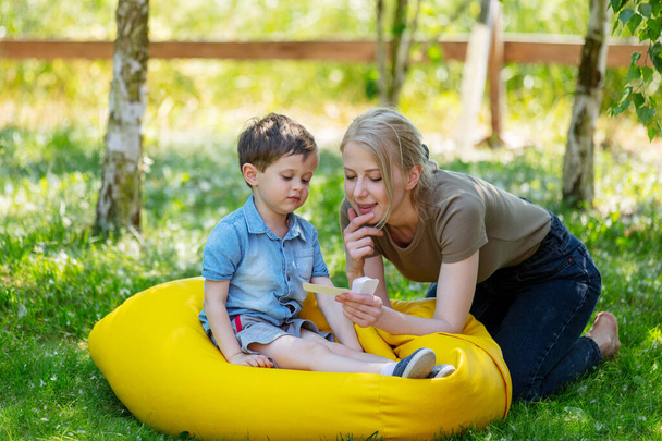 maman enseigne à prononcer des mots en utilisant la technique Doman pour un enfant autiste dans la cour  - Photo, image