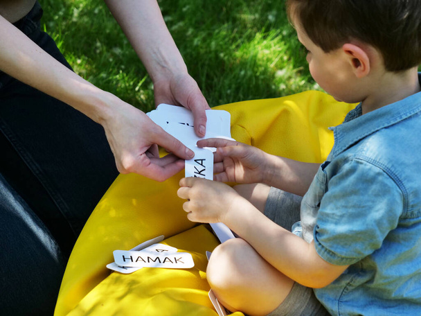 Moeder leert uit te spreken woorden met behulp van de Doman techniek voor een autistisch kind in de tuin - Foto, afbeelding