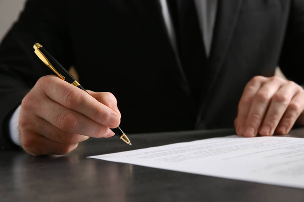 Male notary signing document at table, closeup - Φωτογραφία, εικόνα