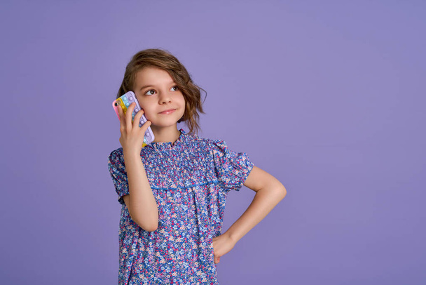 Little girl holding telephone isolated over violet color background - Foto, Imagen
