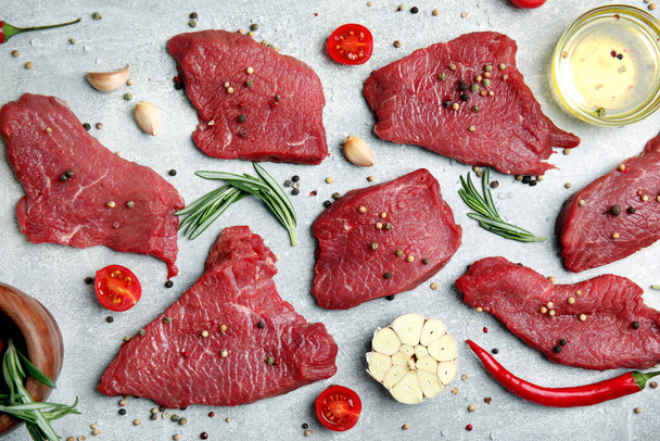 Fresh raw meat steaks and spices on light grey table, flat lay - Photo, Image