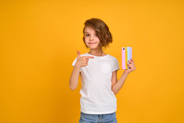 Little girl holding telephone isolated over yellow color background - Фото, зображення