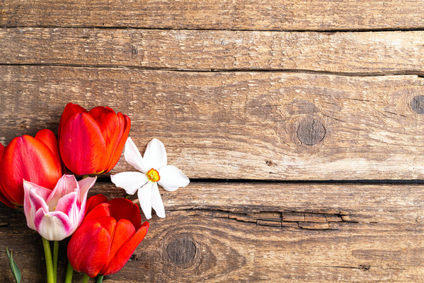 Slavnostní květinové složení tulipánových květin, narcis na starém dřevěném pozadí. Koncept jarních prázdnin pozadí. Hromada tulipánů kvete. Velikonoční a jarní přání, pohled shora. Kopírovat prostor - Fotografie, Obrázek