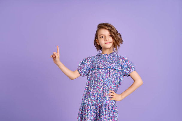 Look There. Excited Caucasian Kid Girl Pointing Thumb At Free Space For Text Posing On Purple Studio Background. Panorama - Foto, Imagen