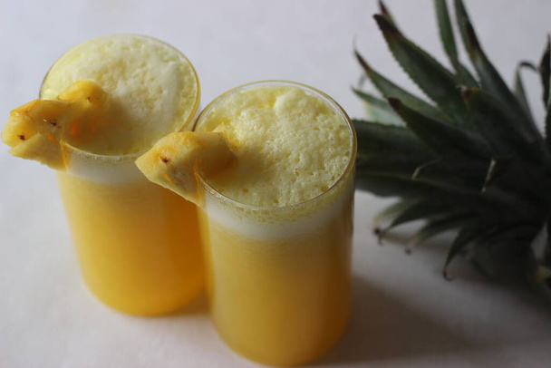 Охолоджений ананасовий сік, щоб побити літню спеку. Домашній сік подають у довгому склі, прикрашеному ананасовим клином. Знімок на білому тлі
 - Фото, зображення
