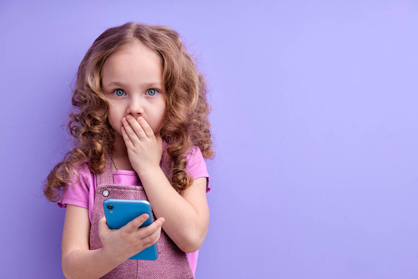 Páni, úžasná aplikace pro děti. užaslá holčička používající smartphone s šokovaným výrazem - Fotografie, Obrázek