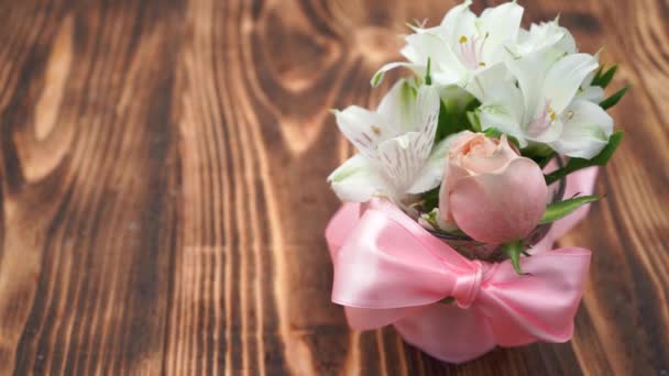 Boeket bloemen tijdens sneeuwval, roze lint, houten achtergrond close-up - Video